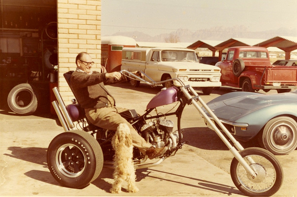 Man with his motorized tricycle at a garage, ca. 1970s.jpg
